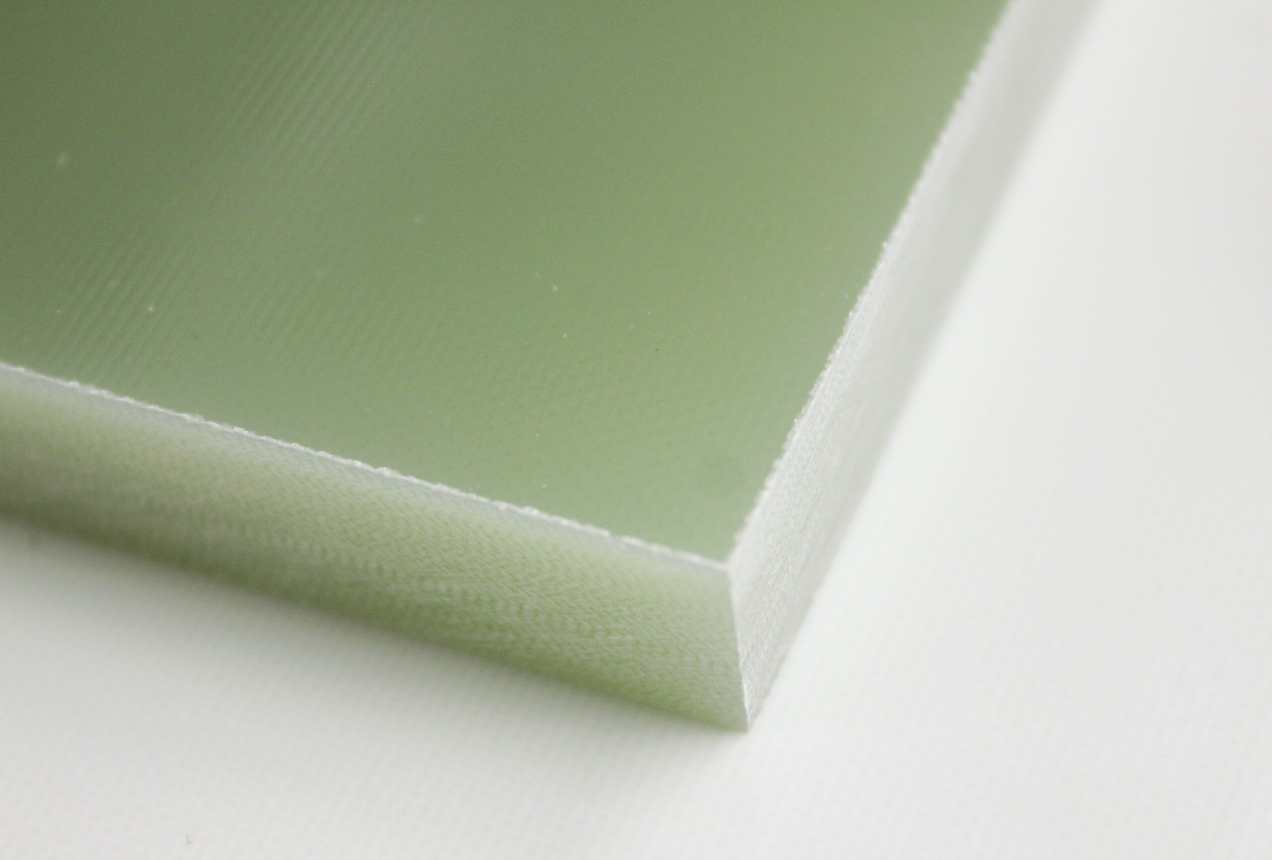 A pale green rectangular sheet rests on a white surface; its edge is visible, showing a slightly textured, layered structure.